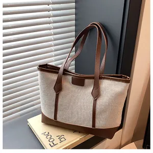 Close-up of the textured beige canvas and brown leather trim on a stylish tote bag