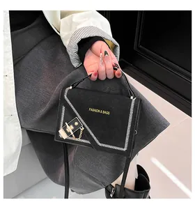 Detail of black crossbody bag with white V-stitching and gold logo lettering