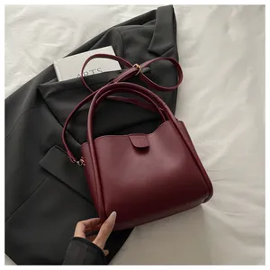 Close-up of wine red matte leather bucket bag with top handle and adjustable strap