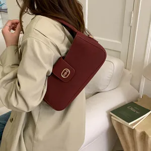 Side view of a vintage burgundy textured fabric baguette bag with a gold buckle