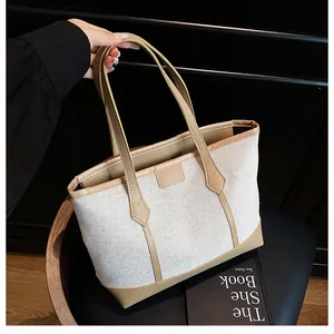 Detail of canvas tote bag with khaki leather trim and handles in a minimalist setting