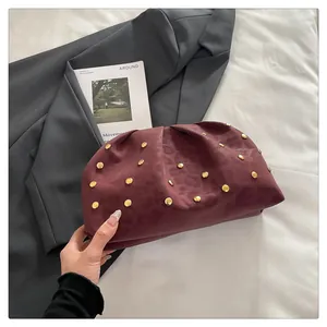 Detail of burgundy ruched clutch bag featuring gold studs and leopard texture suede