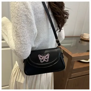 Detailaufnahme der rosa Schmetterlingsstickerei auf einer schwarzen Kunstledertasche
