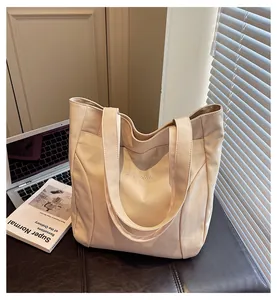 Close-up of cream canvas tote bag with front pocket and embroidery on a desk