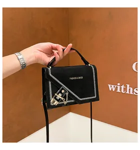 Detail of black suede handbag with V-shaped woven stitching and golden metal lock
