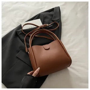 Top view of brown minimalist bucket bag with adjustable strap on a black blazer