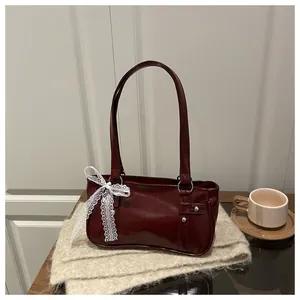 Detail of burgundy glossy handbag with elegant white lace bow and silver metal hardware