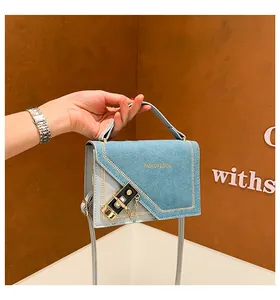 Close-up of light blue handbag showing V-stitch details and gold fashion logo engraving