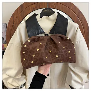 Close-up of brown leopard print cloud clutch featuring golden studs and pleated texture