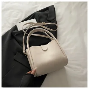 Top-down view of cream leather bucket bag with top handles and a detachable strap