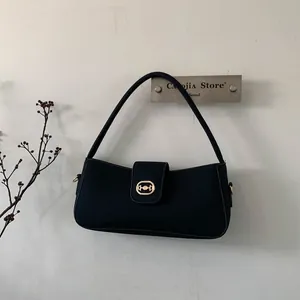 Detail of minimalist black tote bag with gold horsebit buckle hanging on a wall