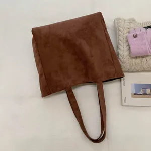 Detail of dark brown suede tote bag with slim shoulder straps in a winter setting