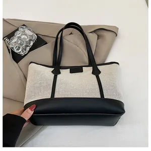 Close-up of contrast stitching and black leather trim on a stylish canvas tote bag