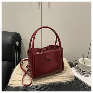 Detail view of burgundy bucket bag with three compartments and adjustable strap