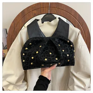Close-up of black leopard print pleated bag with gold rivet accents and leather strap
