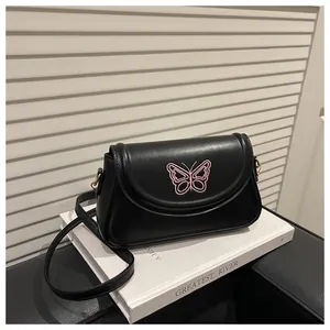 Détail de la broderie papillon rose sur le sac bandoulière noir en similicuir et doré