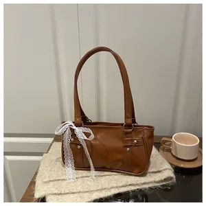 Brown faux leather shoulder bag detail with silver rivets and white lace ribbon decoration