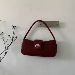 Detailed close-up of burgundy suede shoulder bag with elegant golden metal clasp