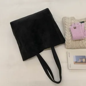 Flat lay of a large black suede tote bag with long handles for winter styling