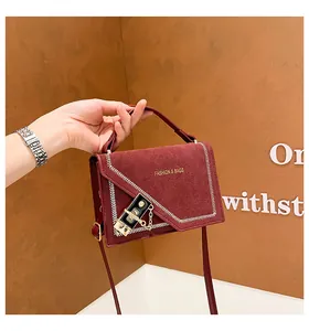 Detail of burgundy suede handbag showing white zigzag stitching and metallic lock closure