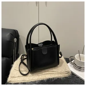Detail view of black leather bucket bag with top handle and gold hardware accessories