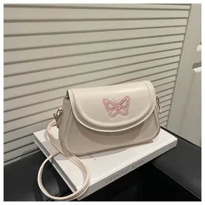 Détail de la broderie papillon rose sur petit sac à rabat blanc cassé en similicuir