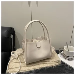 Detail of minimalist cream bucket bag with adjustable strap on soft knit scarf