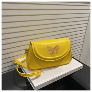 Détail de la broderie papillon rose sur le sac à main jaune en cuir synthétique chic
