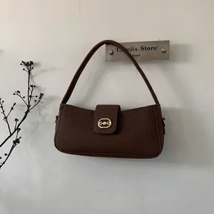 Close-up of deep brown suede shoulder bag with gold interlocking buckle and thin strap