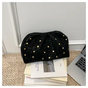 Macro detail of black leopard texture cloud clutch with golden metallic rivet studs
