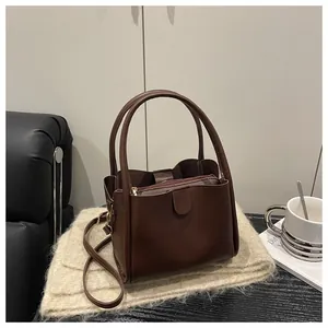 Detail of dark brown bucket bag with magnetic clasp and inner zip pouch on beige fabric