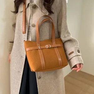 Retro caramel corduroy bucket bag with belt decor worn by model in grey coat