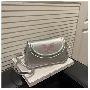 Détail de la broderie papillon rose sur le rabat en cuir argenté brillant du sac