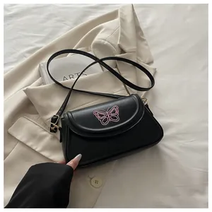 Détail du sac en PU noir avec broderie papillon rose et boucle dorée ajustable