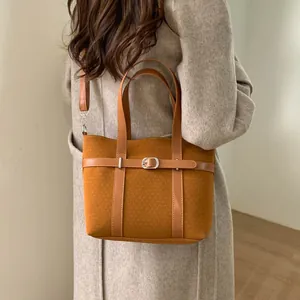Brown textured wool bucket bag with leather strap detailing shown on model