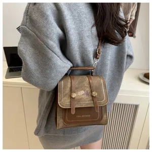 Detail of vintage brown canvas and leather crossbody bag with top handle worn by model