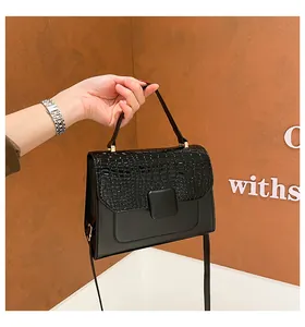 Detail of black faux crocodile skin handbag showing textured flap and metal square buckle