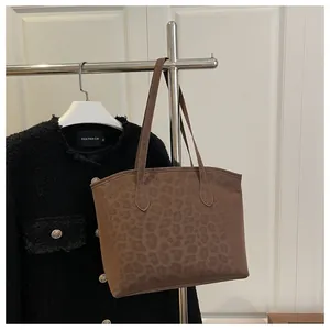 Close-up of leopard print tote bag in brown suede hanging on a metal display stand