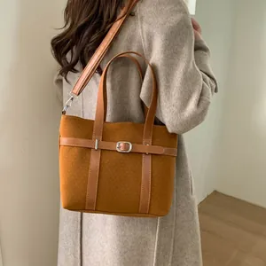 Retro warm brown bucket bag with leather strap detailing worn with a wool coat