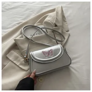 Vue détaillée d'un sac argenté métallique avec broderie papillon rose et boucle dorée