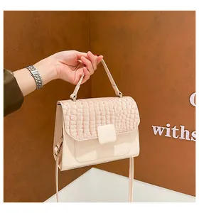 Detail shot of the crocodile embossed texture and square buckle on a beige handbag