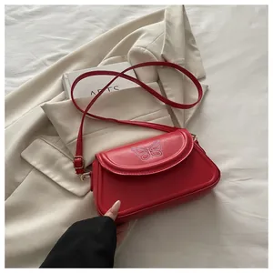 Détail du petit sac rouge avec broderie papillon blanche élégante et texture en cuir PU