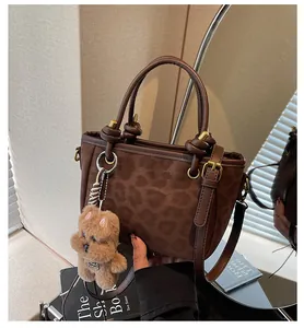 Detail einer braunen Beuteltasche mit Leopardenmuster und Plüschbär-Anhänger