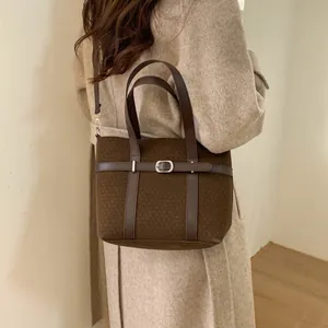 Detail of retro dark brown wool bucket bag with leather strap and metal buckle accent