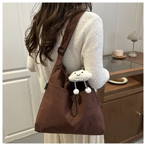 Detail of dark brown canvas tote bag featuring an adjustable strap and cloud plush charm