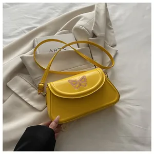 Détail de broderie papillon rose sur petit sac à bandoulière en cuir PU jaune vif