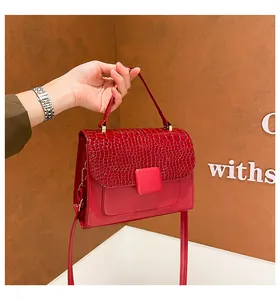 Detail of red crocodile texture flap and golden hardware on woman's luxury handbag