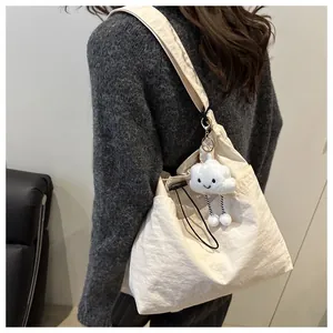 Detail of minimalist cream drawstring tote bag with a cute white plush cloud charm