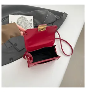 Top view of open red faux leather crossbody bag showing interior lining and gold clasp