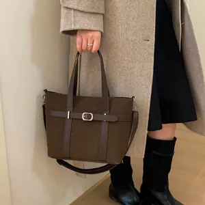 Deep brown bucket bag with belt detail and silver buckle shown with stylish winter outfit